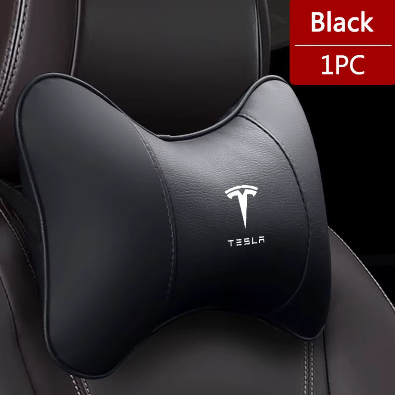 Black car headrest pillow with Tesla logo on a black car interior.