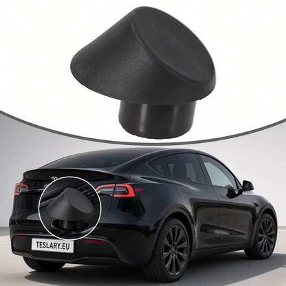 A black textured dome-shaped cover or cap shown floating above a black Tesla Model Y, with a circular inset highlighting the corresponding area on the vehicle. The background is a clean white studio-style backdrop. Tesla Trunk Rubber Stopper 1507940-00-C and 1507942-00-C Buy from Ireland and Europes teslary.eu