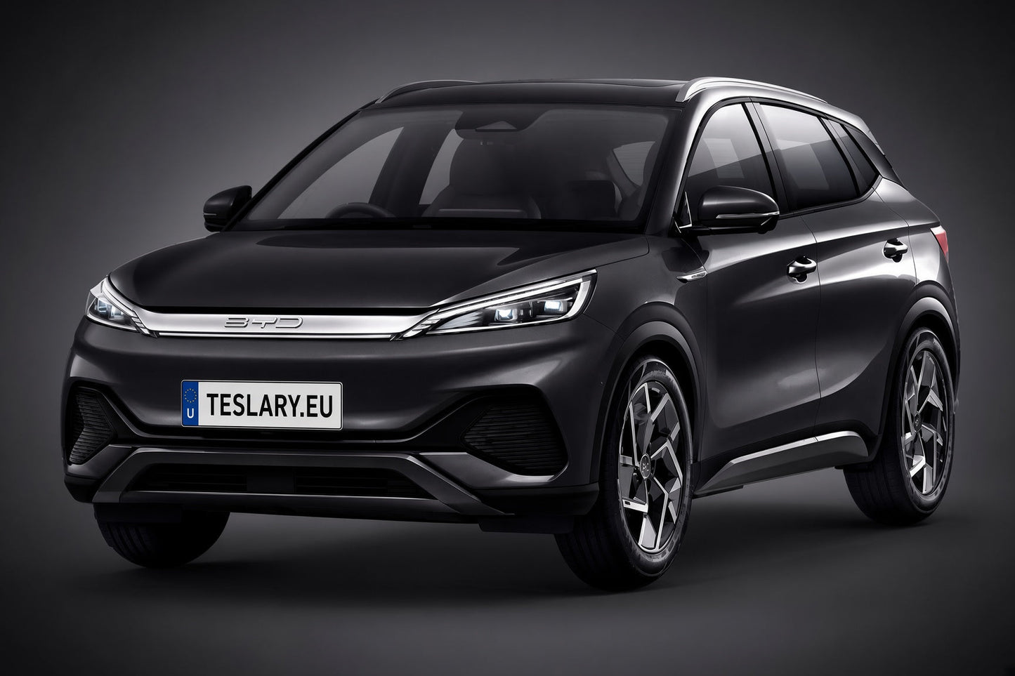 BYD ATTO3 EV ACCESSORIES BUY FROM EUROPES TESLARY.EU A dark metallic gray BYD SUV with a custom license plate reading 'TESLARY.EU', shown from a three-quarter front angle against a dark gray studio background.