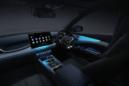 A luxury car interior with a large touchscreen display, a curved dashboard, a multi-spoke steering wheel, and blue ambient lighting along the door panel and console. The seats are upholstered in a light blue and dark gray material with subtle red stitching.