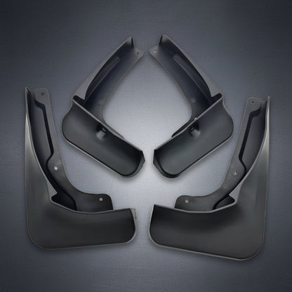 Quatre bavettes de protection noires en plastique pour véhicules, disposées symétriquement sur un fond blanc uni.